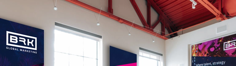 Interior of a modern office with exposed red beams, featuring promotional banners for brk global marketing.