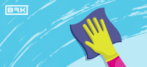 Illustration of a hand in a yellow glove cleaning a blue surface with a purple cloth, BRK logo in the corner.