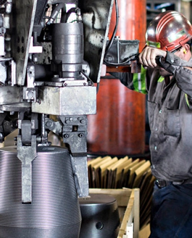 Worker in protective gear operates heavy machinery in an industrial setting.