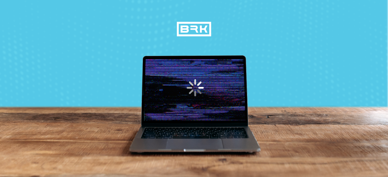 A laptop on a wooden table with a glitchy loading screen, against a blue background with a “BRK” logo above.
