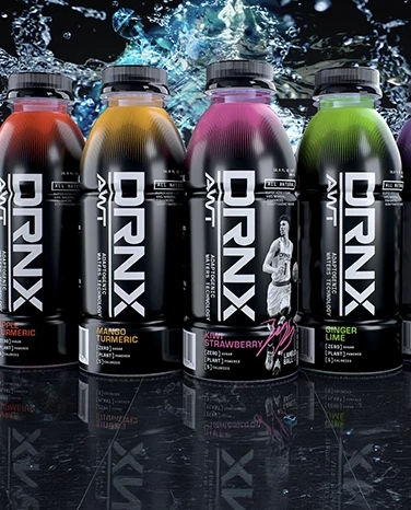 Five colorful DRNX drink bottles with fruit flavors are displayed against a splashy water background.