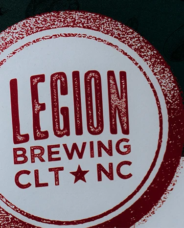 Red and white Legion Brewing CLT NC logo with bold, distressed text on a dark background.