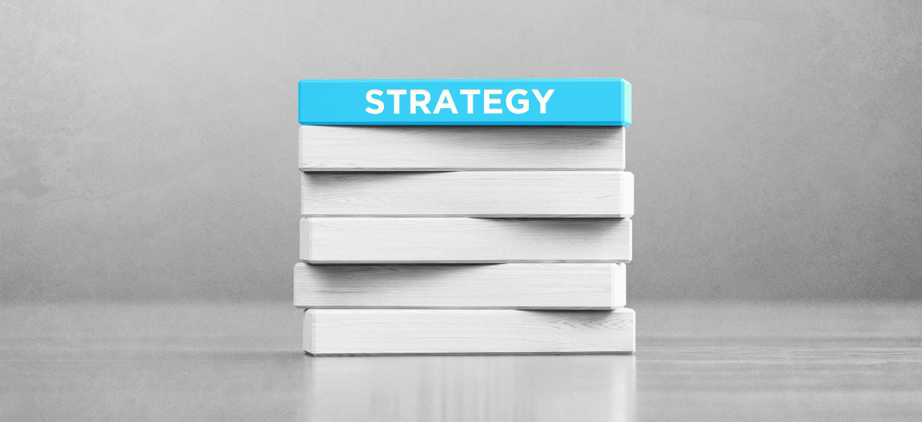 A stack of white books with a blue book on top labeled "STRATEGY" against a gray background.