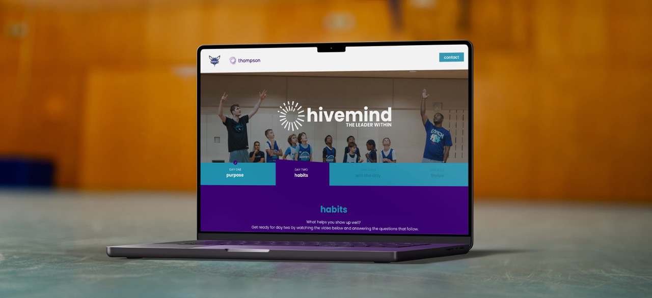 A laptop displays a website with the logo “hivemind” and navigation tabs including “purpose,” “habits,” and “the story,” set against a blurred indoor background.